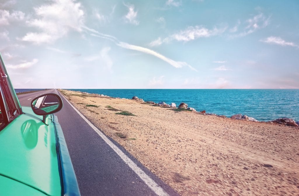 Car side mirror driving next to beach